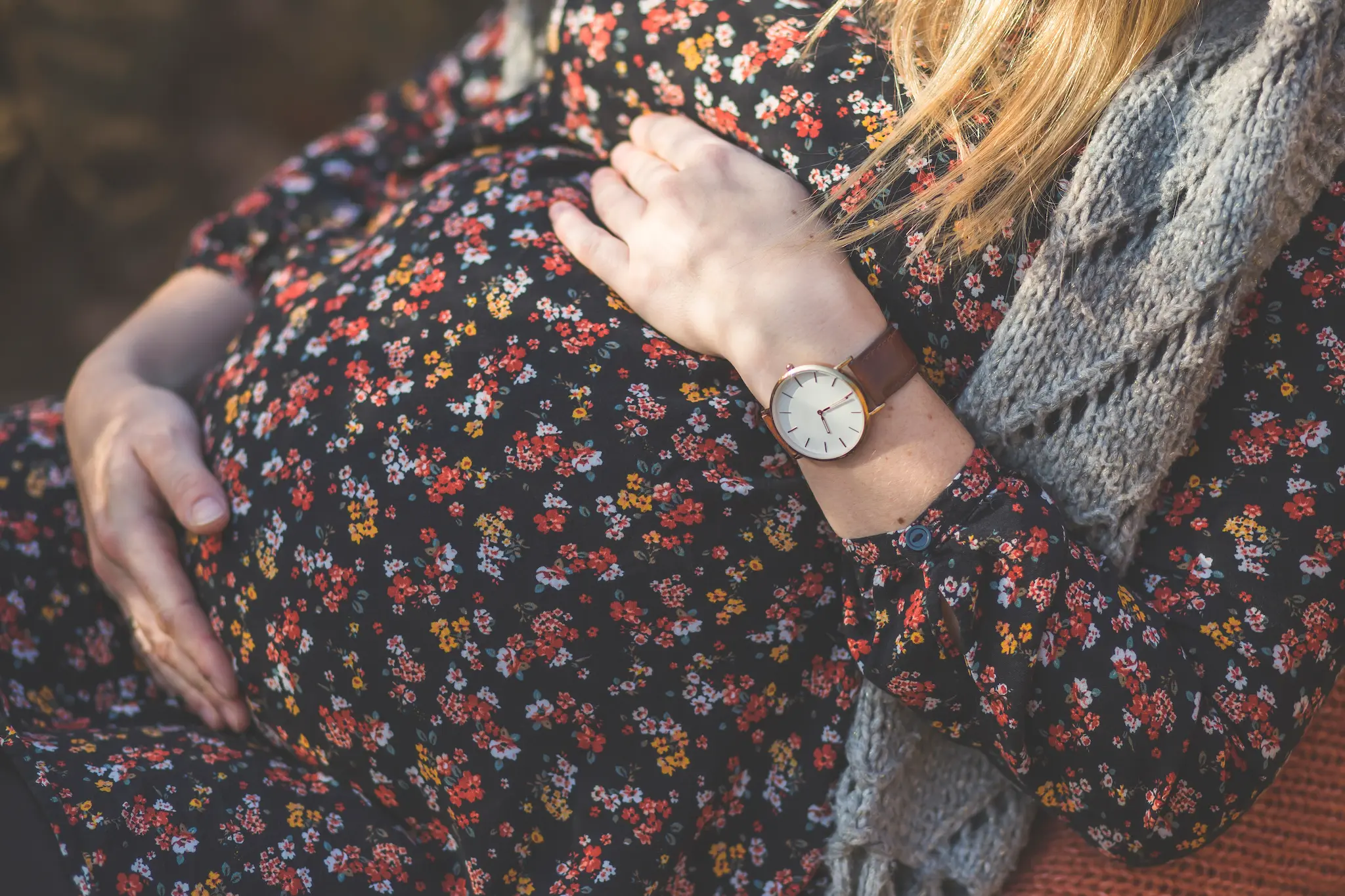 Mujer embarazada con vestido floral y reloj, simbolizando el debate jurídico sobre la gestación subrogada y su reconocimiento en España.